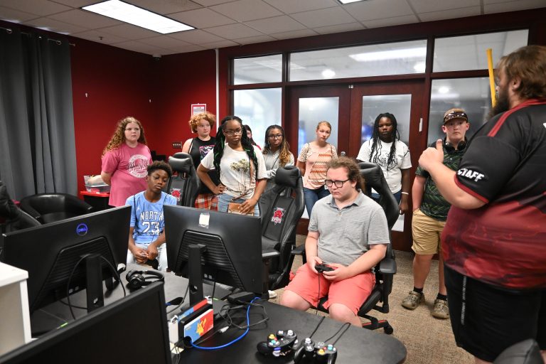 Concord E-Sports talks to students while standing in front computers