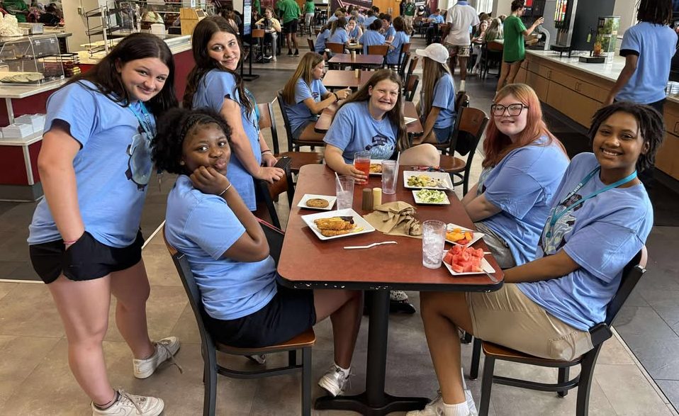 Students sitting in a cafeteria, most smiling