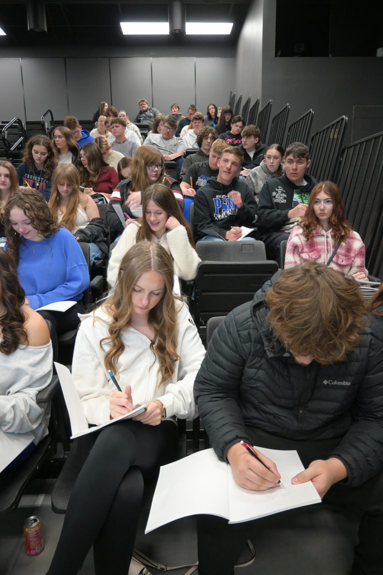 Students writing in work books in a stadium classroom