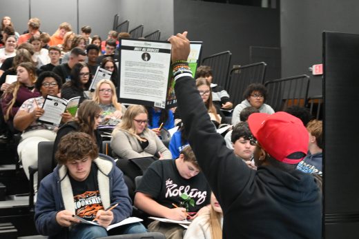 MJ Bridges holds up a book to students during a financial literacy session.