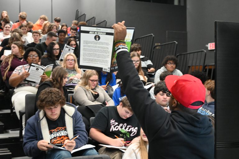 MJ Bridges holds up a book to students during a financial literacy session.