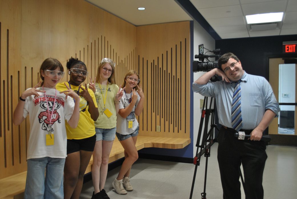 group of students and 59 News reporter pose and smile at camera