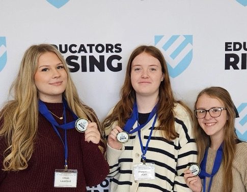 Three girls standing next to each other wearing lanyards