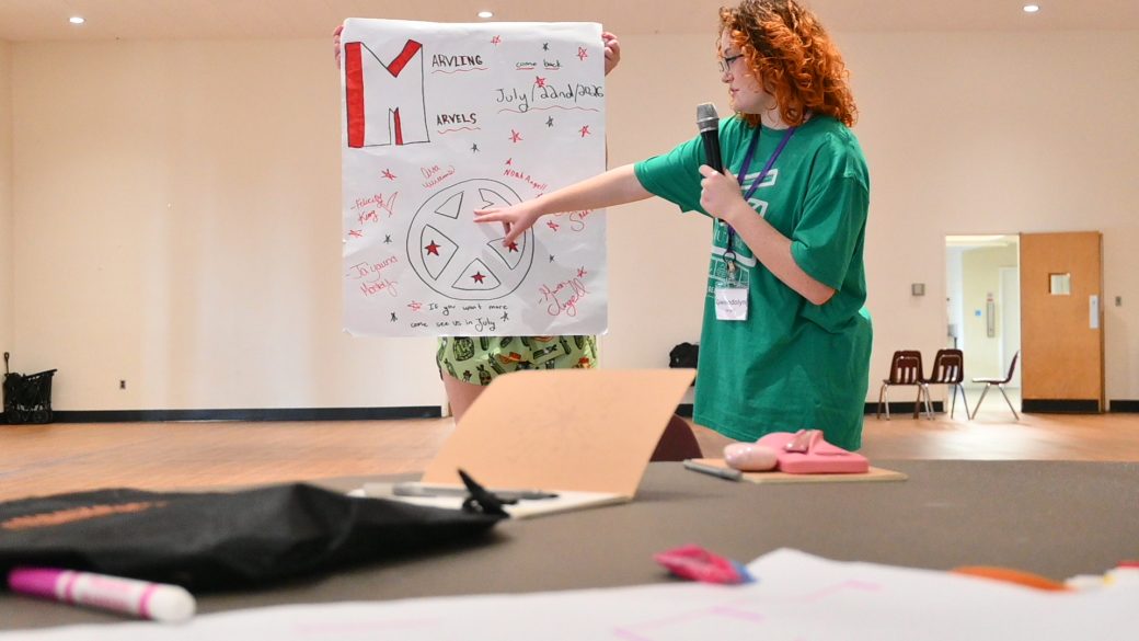 girl in green shirt points to paper