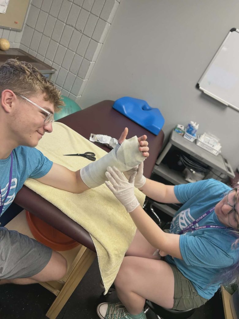 boy smiling while a girl works on his cast